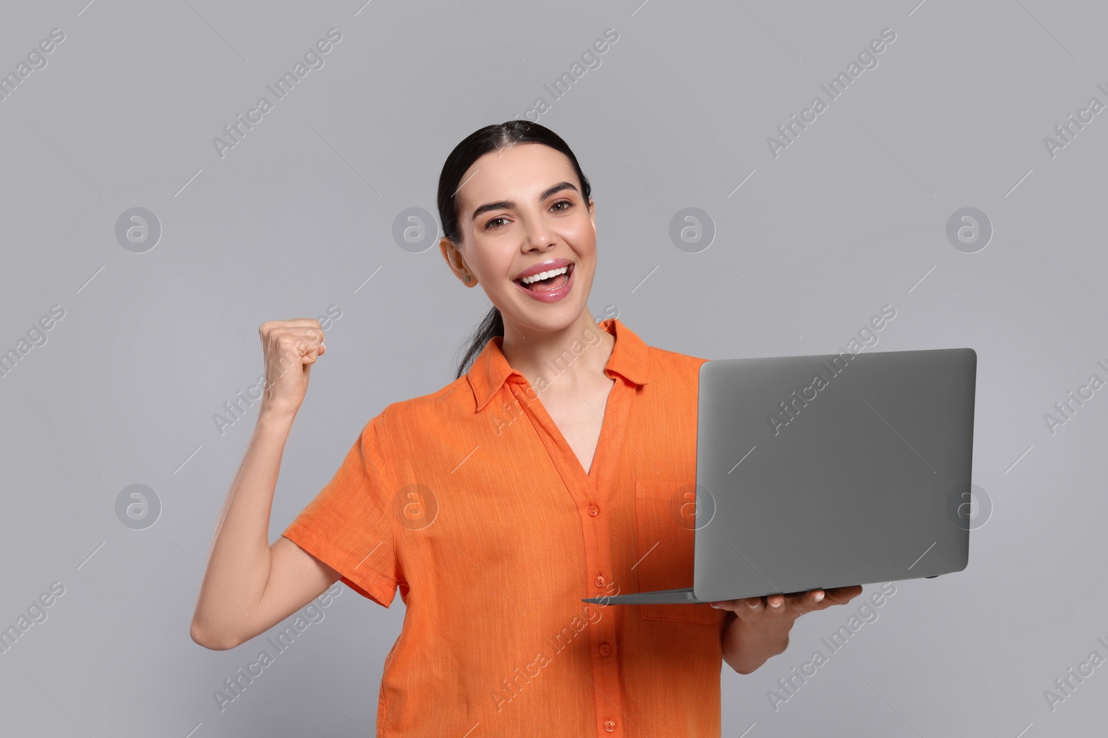 Photo of Happy woman with laptop on light gray background