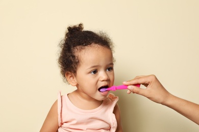 Photo of Woman and her African-American daughter with toothbrush on color background