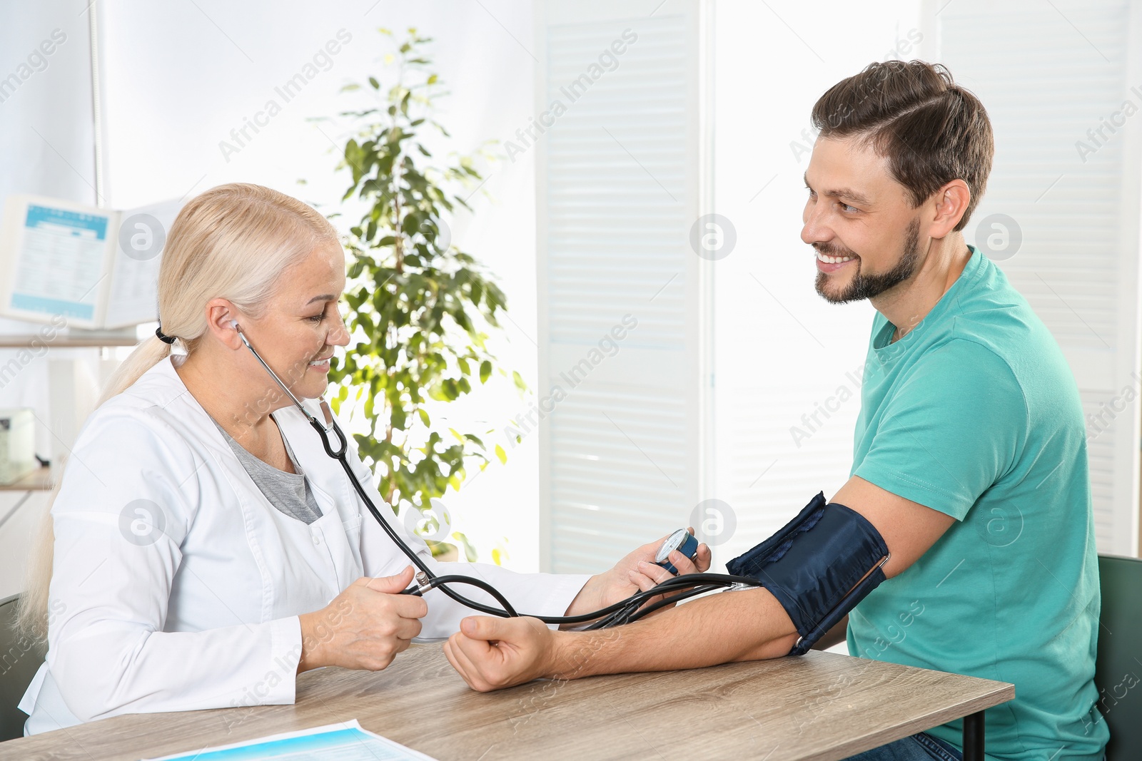Photo of Man visiting doctor in hospital. Measuring blood pressure and checking pulse
