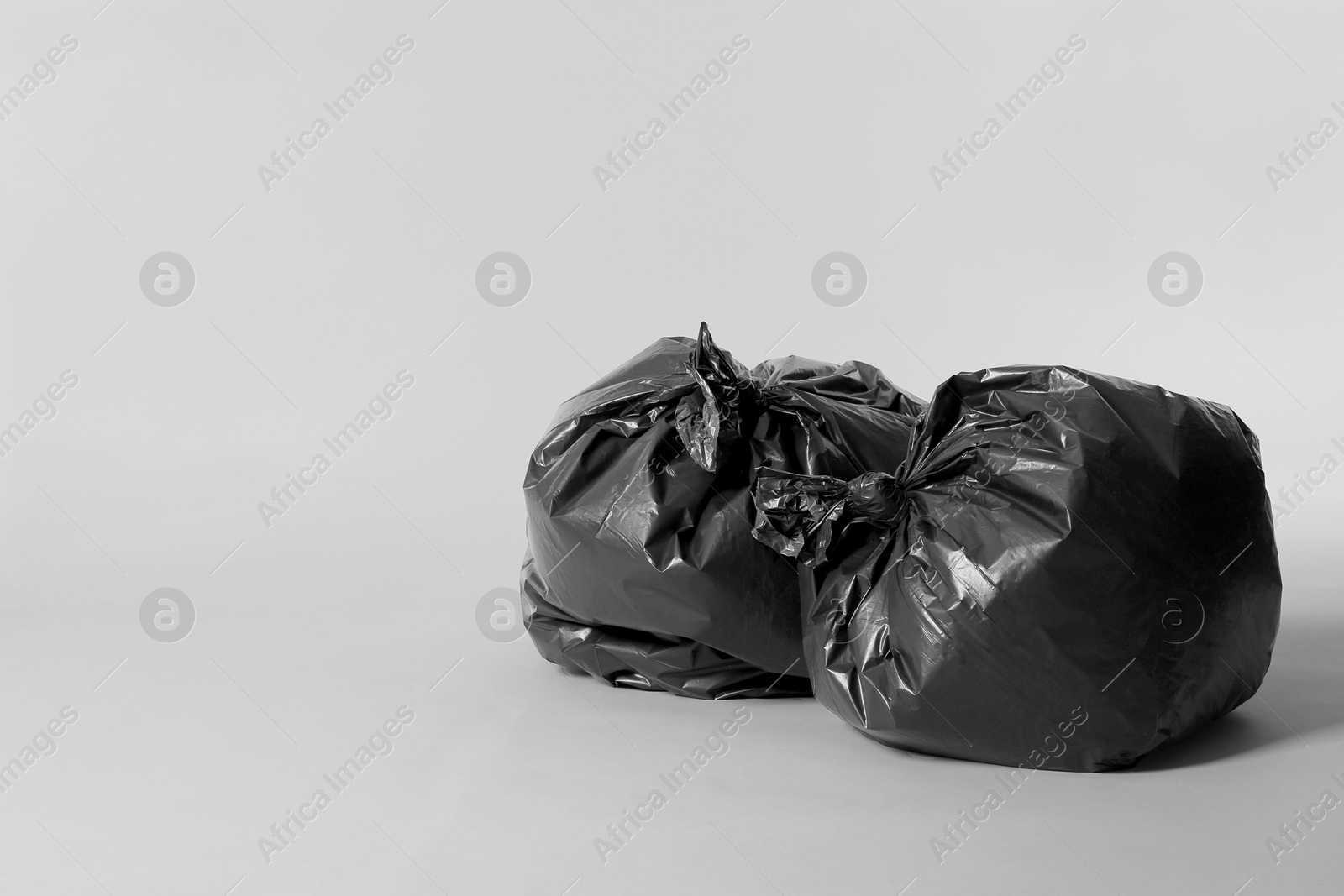 Photo of Trash bags full of garbage on light grey background. Space for text