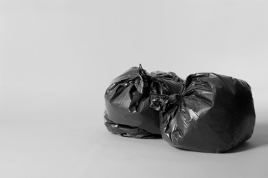 Trash bags full of garbage on light grey background. Space for text