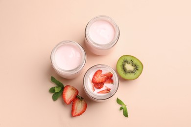 Jars of fresh yogurt, strawberry and kiwi on light pink background, flat lay