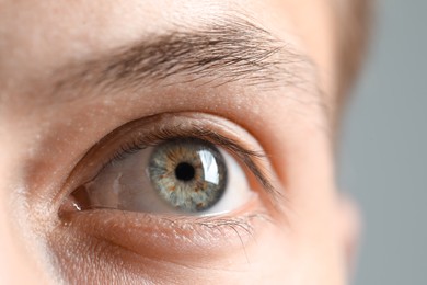 Photo of Perfect vision. Man with beautiful eyes on grey background, closeup