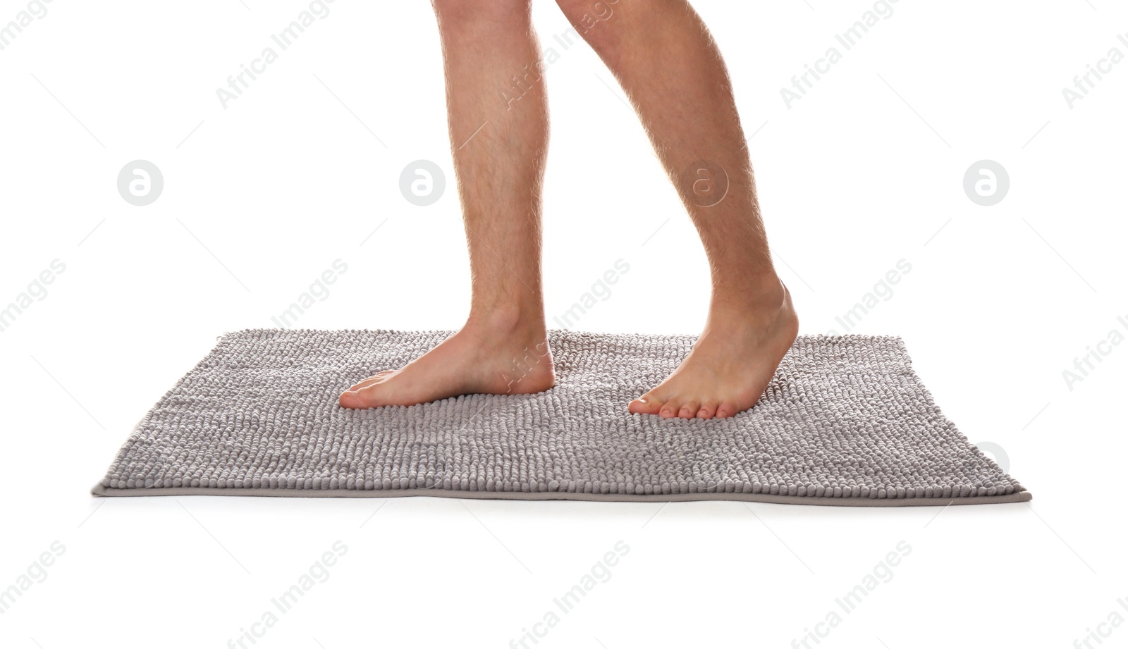 Photo of Man standing on soft grey bath mat against white background, closeup
