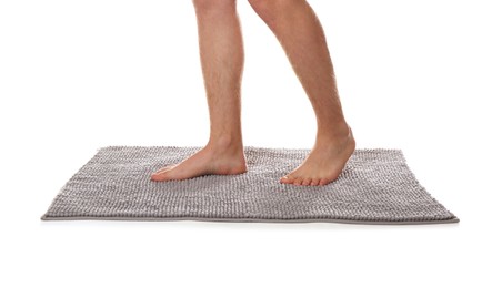 Man standing on soft grey bath mat against white background, closeup