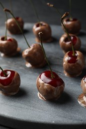 Sweet chocolate dipped cherries on grey board