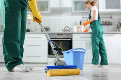 Photo of Cleaning service team at work in kitchen, closeup
