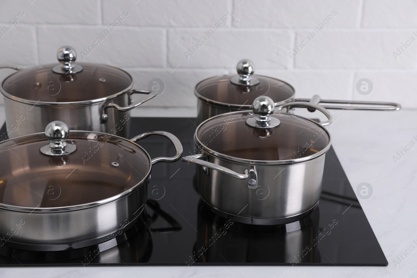 Photo of Set of new clean cookware on cooktop in kitchen