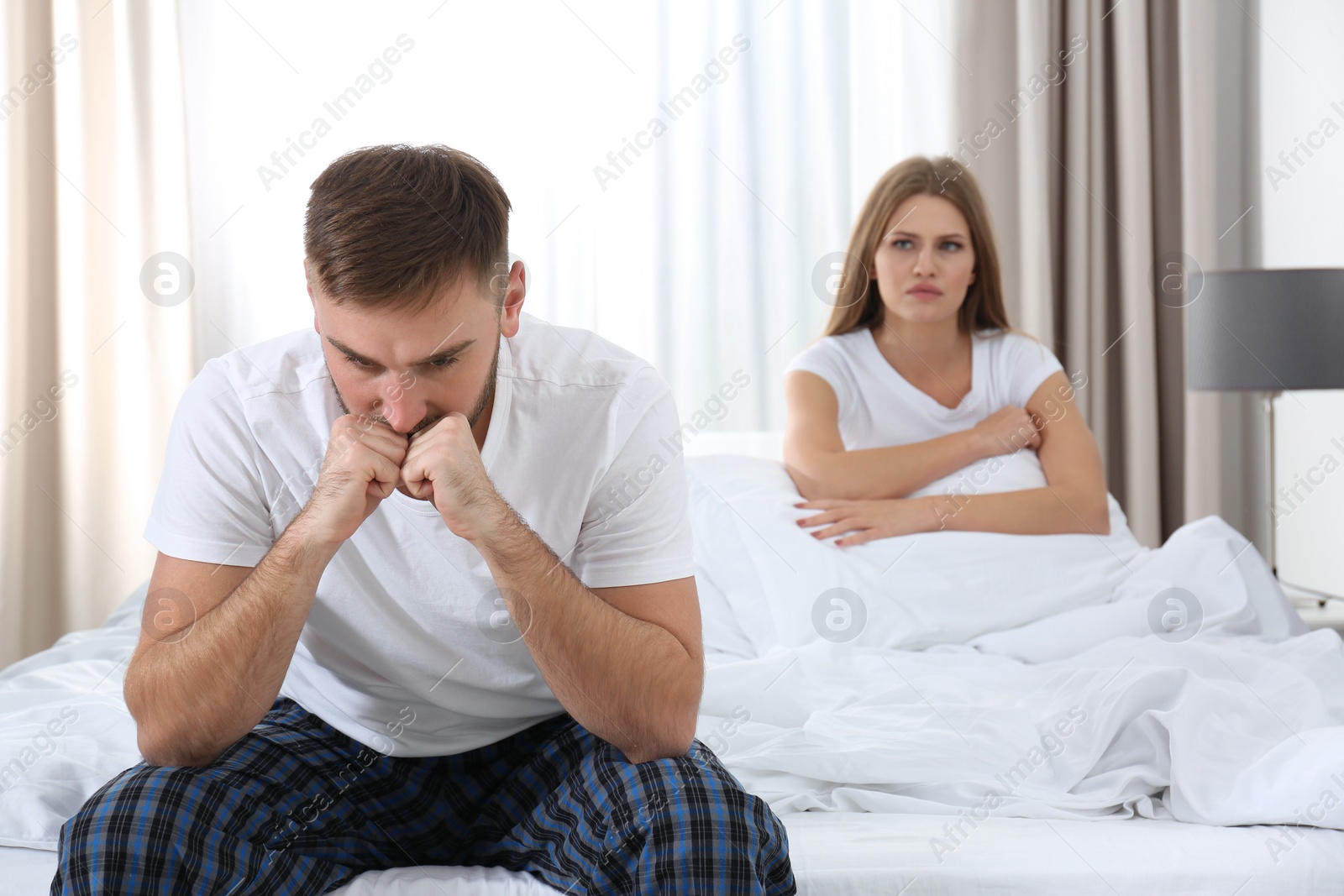 Photo of Young couple with relationship problems ignoring each other in bedroom