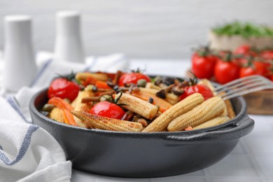 Photo of Tasty roasted baby corn with tomatoes, capers and mushrooms on white tiled table, closeup