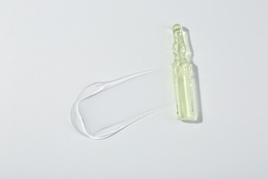 Skincare ampoule on white surface with gel, top view