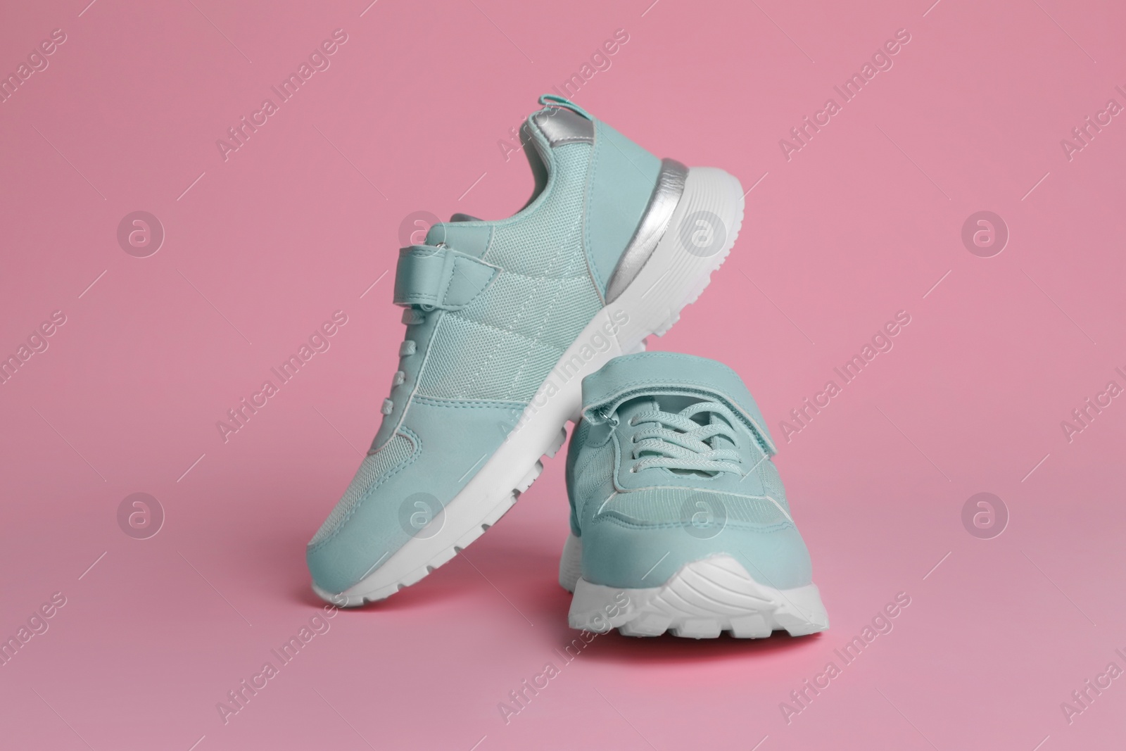 Photo of Pair of stylish sneakers on pink background