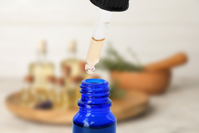 Little bottle with essential oil and dropper against blurred background 