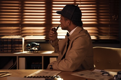 Old fashioned detective with smoking pipe at table in office