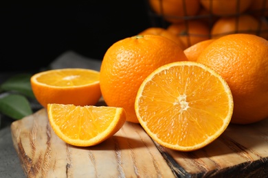 Photo of Wooden board with ripe oranges on table, closeup