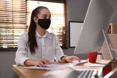 Photo of Female worker with mask in office. Protective measure during COVID-19 pandemic