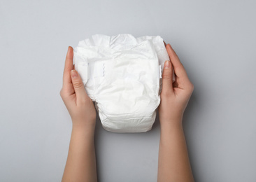 Photo of Woman with diaper on light grey background, closeup