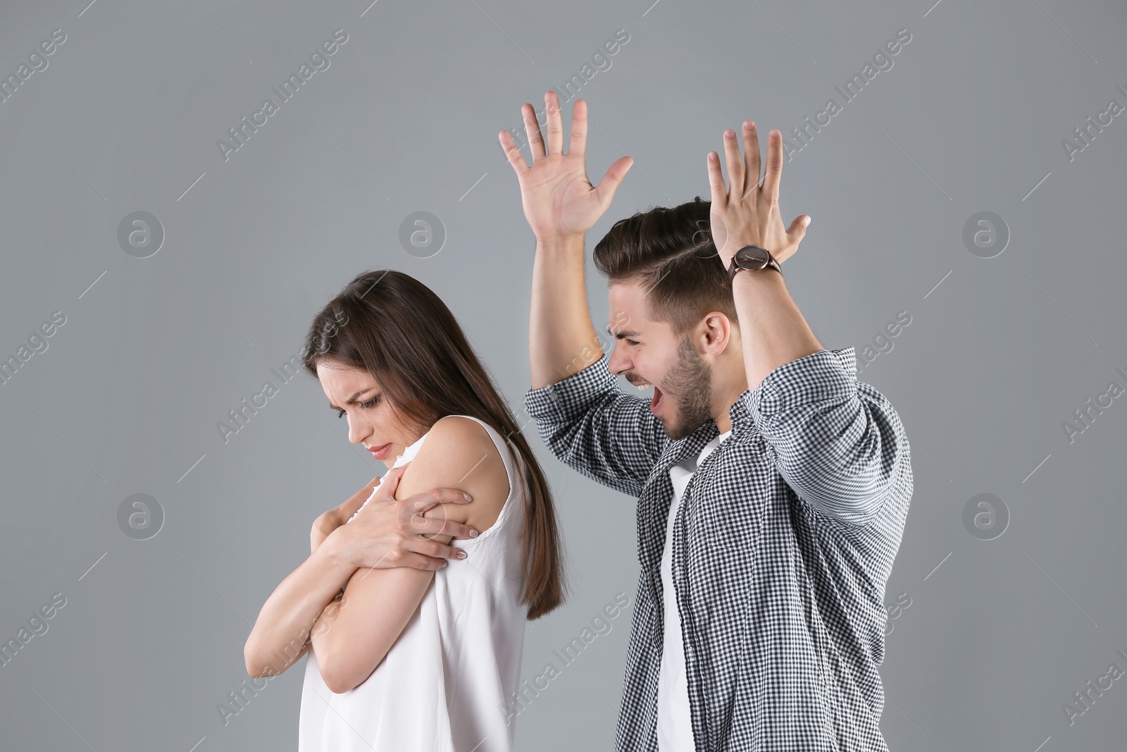 Photo of Young couple having argument on grey background. Relationship problems