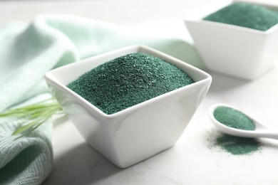 Composition with bowl of spirulina algae powder on table