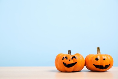 Photo of Pumpkins with scary faces on light blue background, space for text. Halloween decor