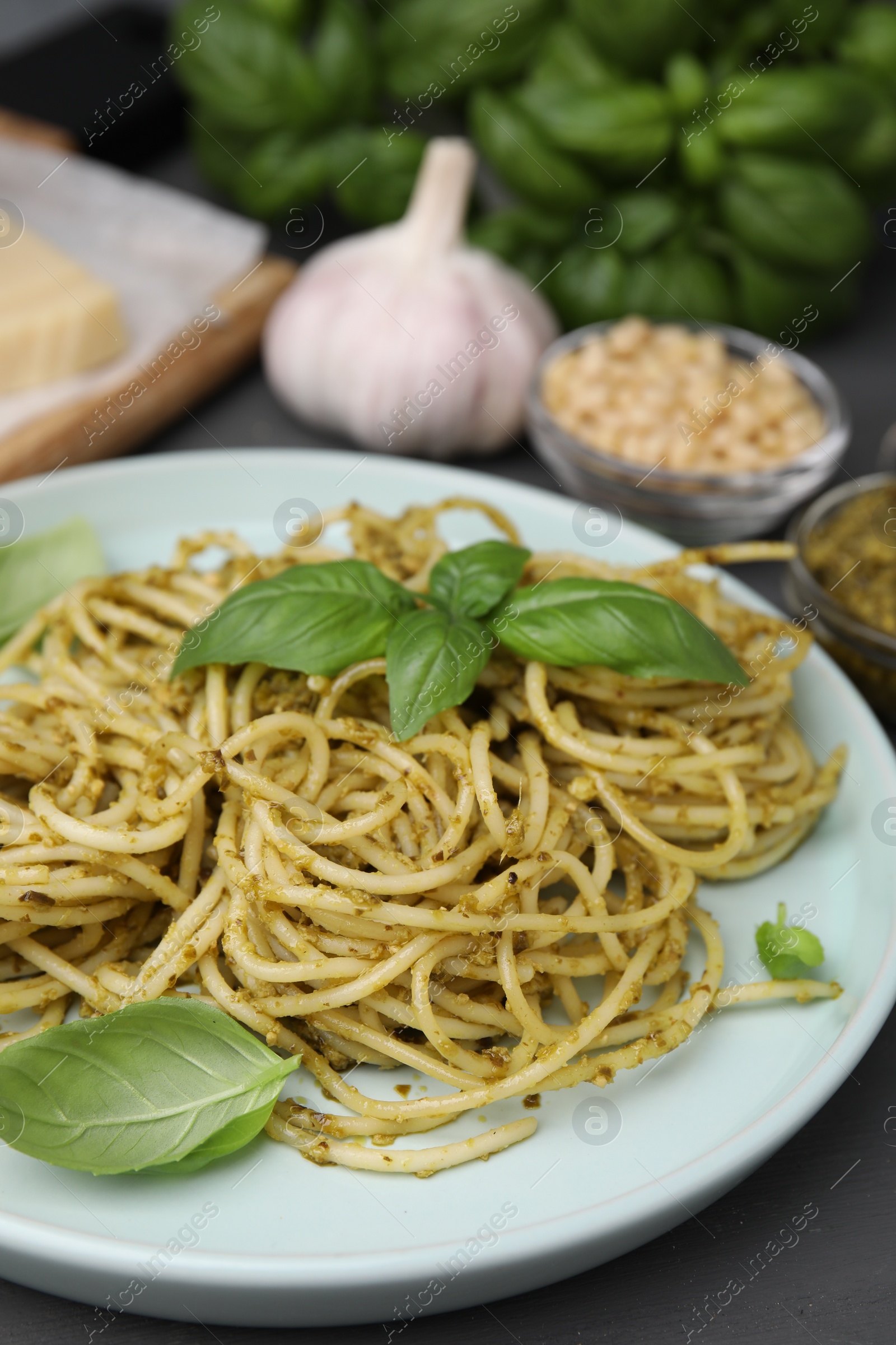 Photo of Delicious pasta with pesto sauce and basil on grey table, closeup