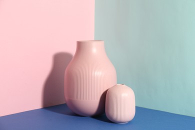 Stylish empty ceramic vases on color background