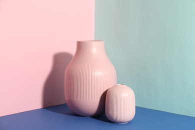 Photo of Stylish empty ceramic vases on color background