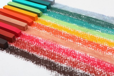 Photo of Colorful pastel chalks on white background, closeup. Drawing materials