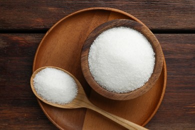 Photo of Granulated sugar in bowl and spoon on wooden table, top view