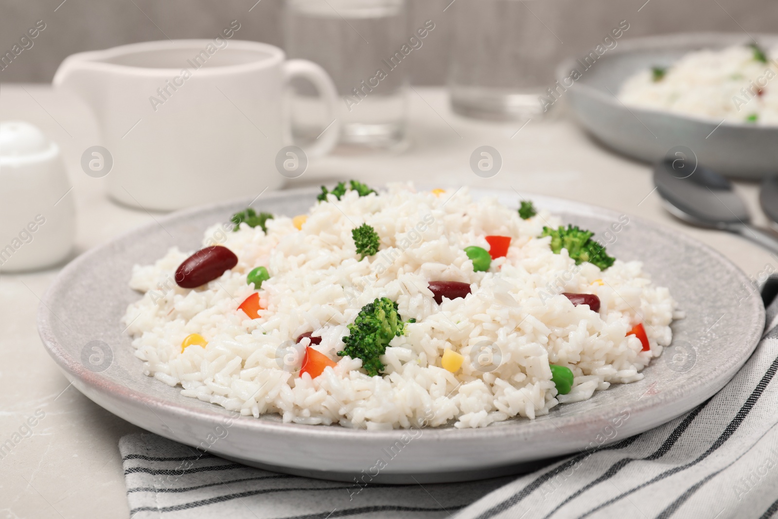 Photo of Plate of boiled rice with vegetables on table