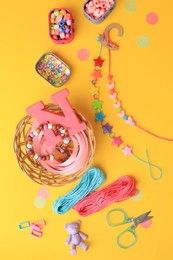 Photo of Handmade jewelry kit for kids. Colorful beads, bracelets and different supplies on orange background, flat lay