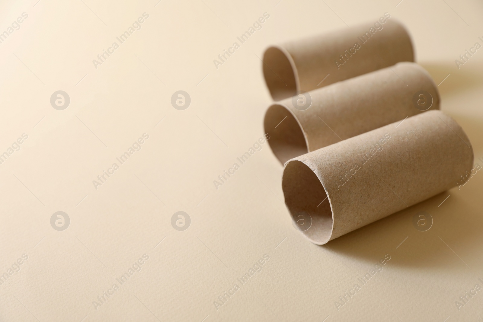 Photo of Empty toilet paper rolls on beige background. Space for text