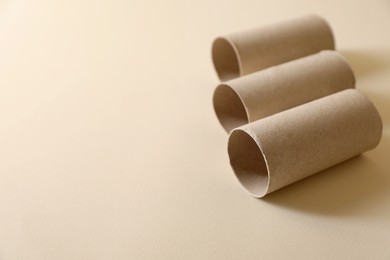 Empty toilet paper rolls on beige background. Space for text