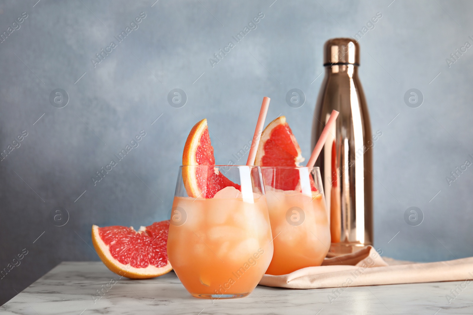 Photo of Glasses of grapefruit cocktails served on table against color background. Space for text