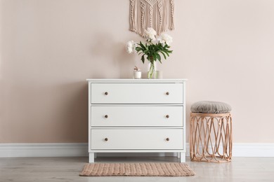 Room interior with white chest of drawers near beige wall