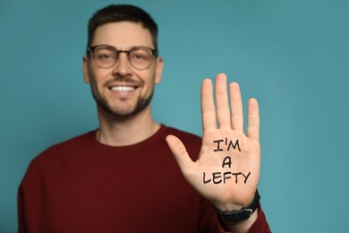 Left-handed man against light blue background, focus on palm with text 