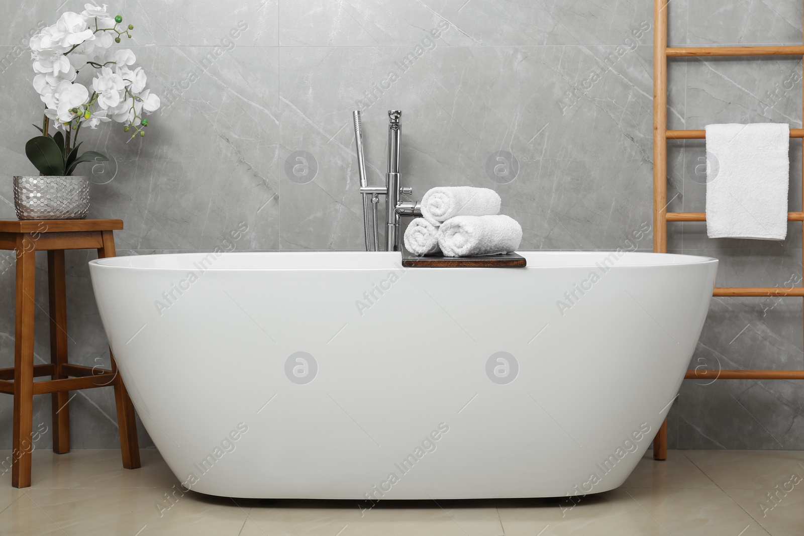 Photo of Rolled bath towels on tub tray in bathroom