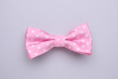 Photo of Stylish pink bow tie with polka dot pattern on light grey background, top view