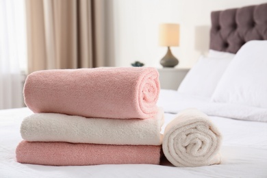 Photo of Folded and rolled soft towels on bed in room. Space for text