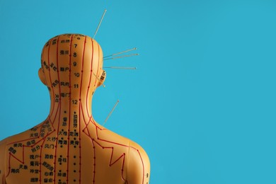 Photo of Acupuncture - alternative medicine. Human model with needles in head and shoulder against light blue background, back view. Space for text