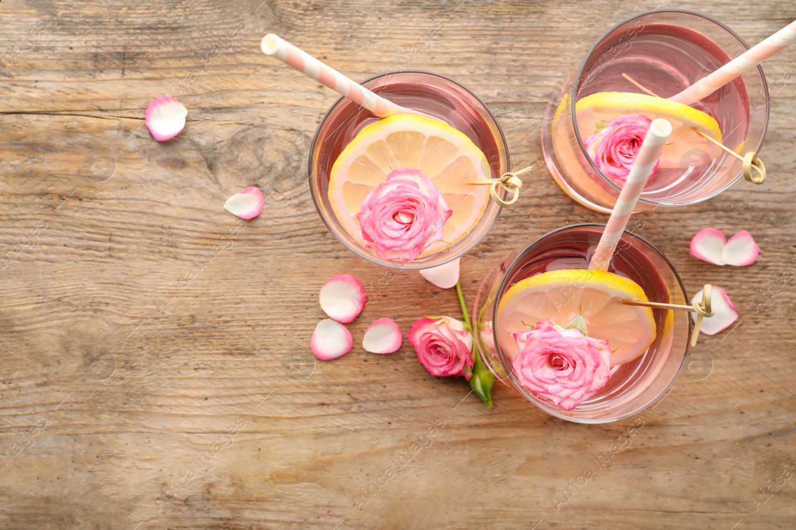 Photo of Refreshing drink with lemon and rose on wooden table, flat lay. Space for text