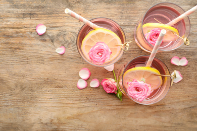 Photo of Refreshing drink with lemon and rose on wooden table, flat lay. Space for text