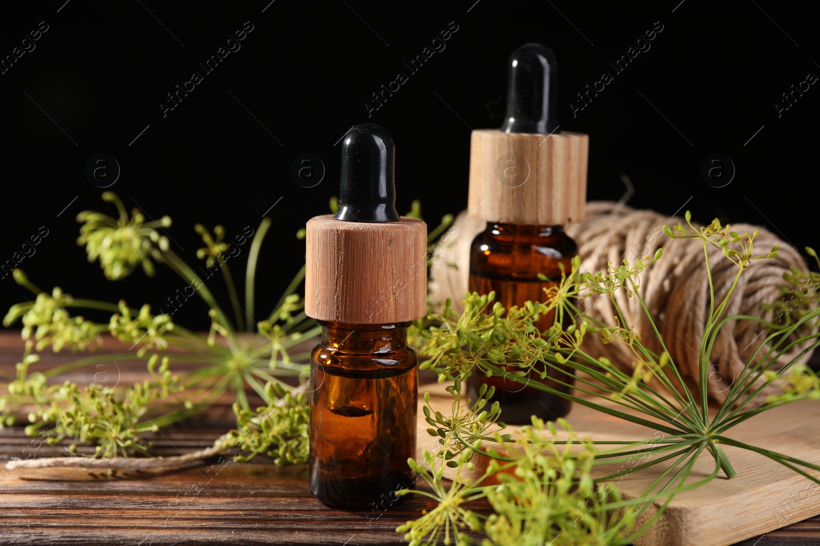 Photo of Bottle of essential oil, fresh dill and twine on wooden table, closeup