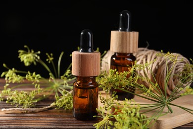 Photo of Bottleessential oil, fresh dill and twine on wooden table, closeup