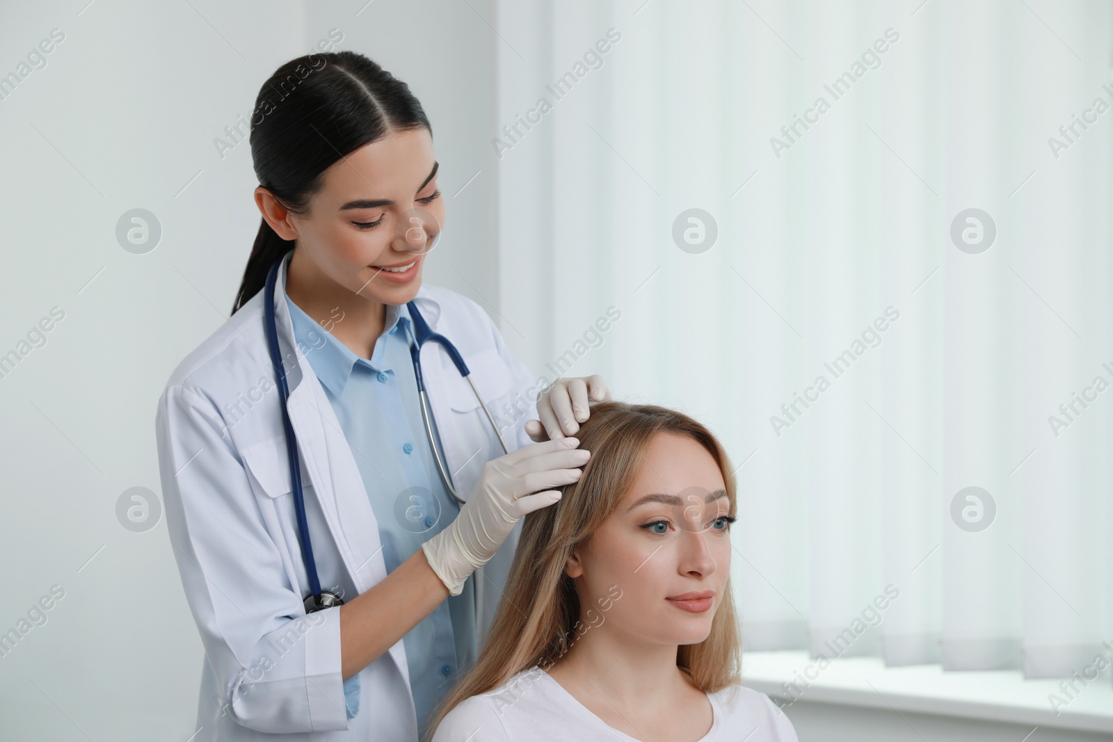 Photo of Young woman visiting trichologist in light clinic