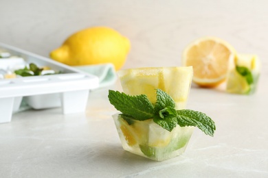 Ice cubes with mint and lemon on table