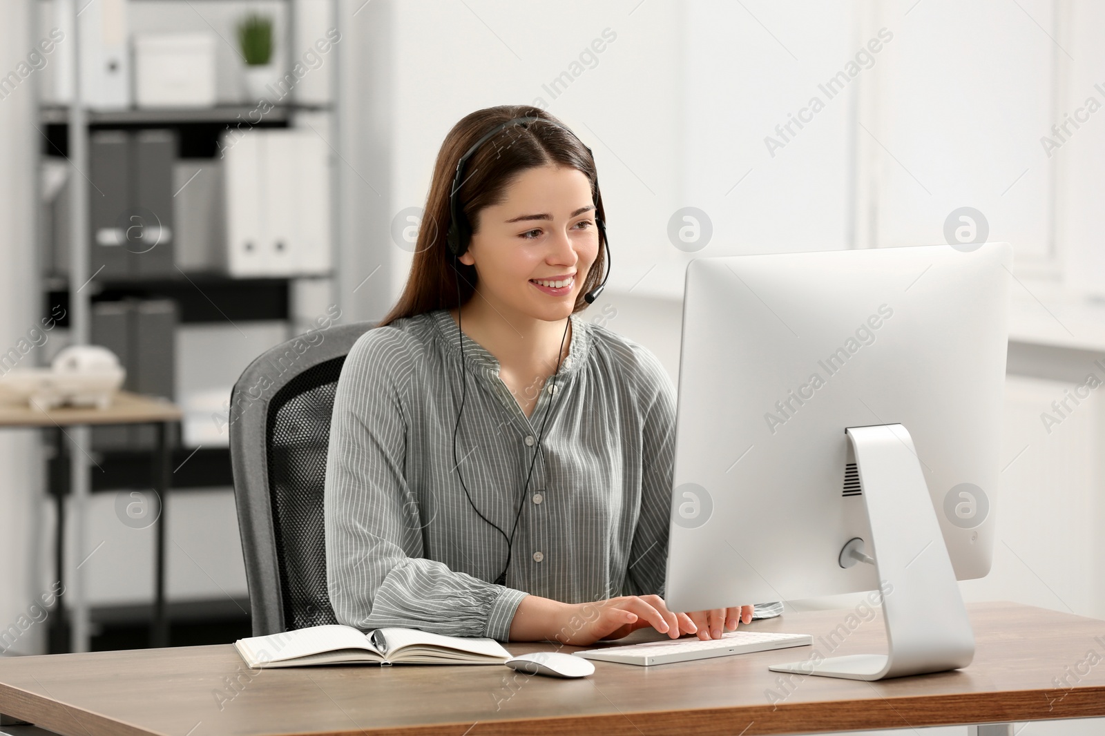 Photo of Hotline operator with headset working on computer in office