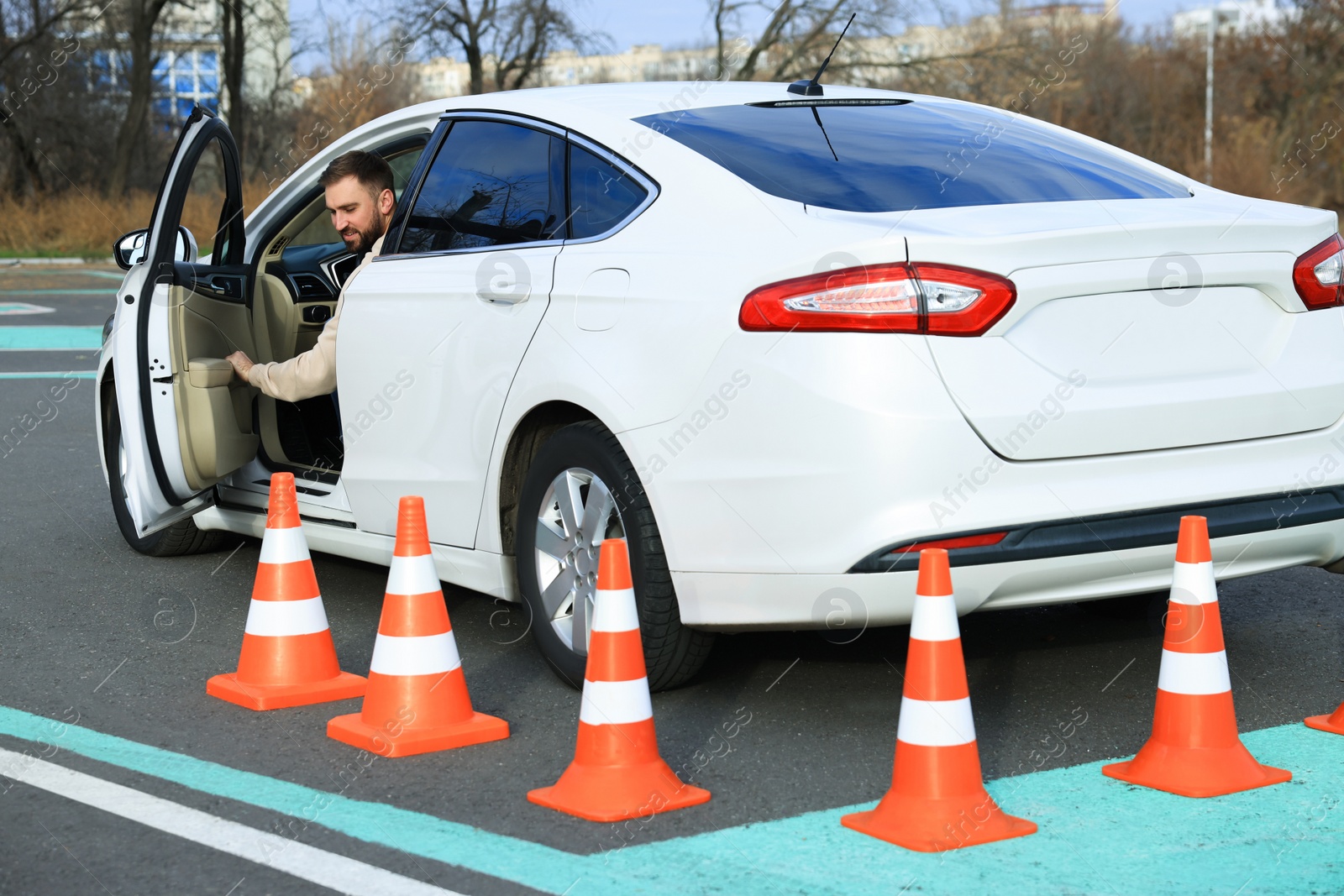 Photo of Young man in car on test track with traffic cones. Driving school