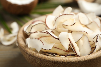 Tasty coconut chips in wooden bowl, closeup