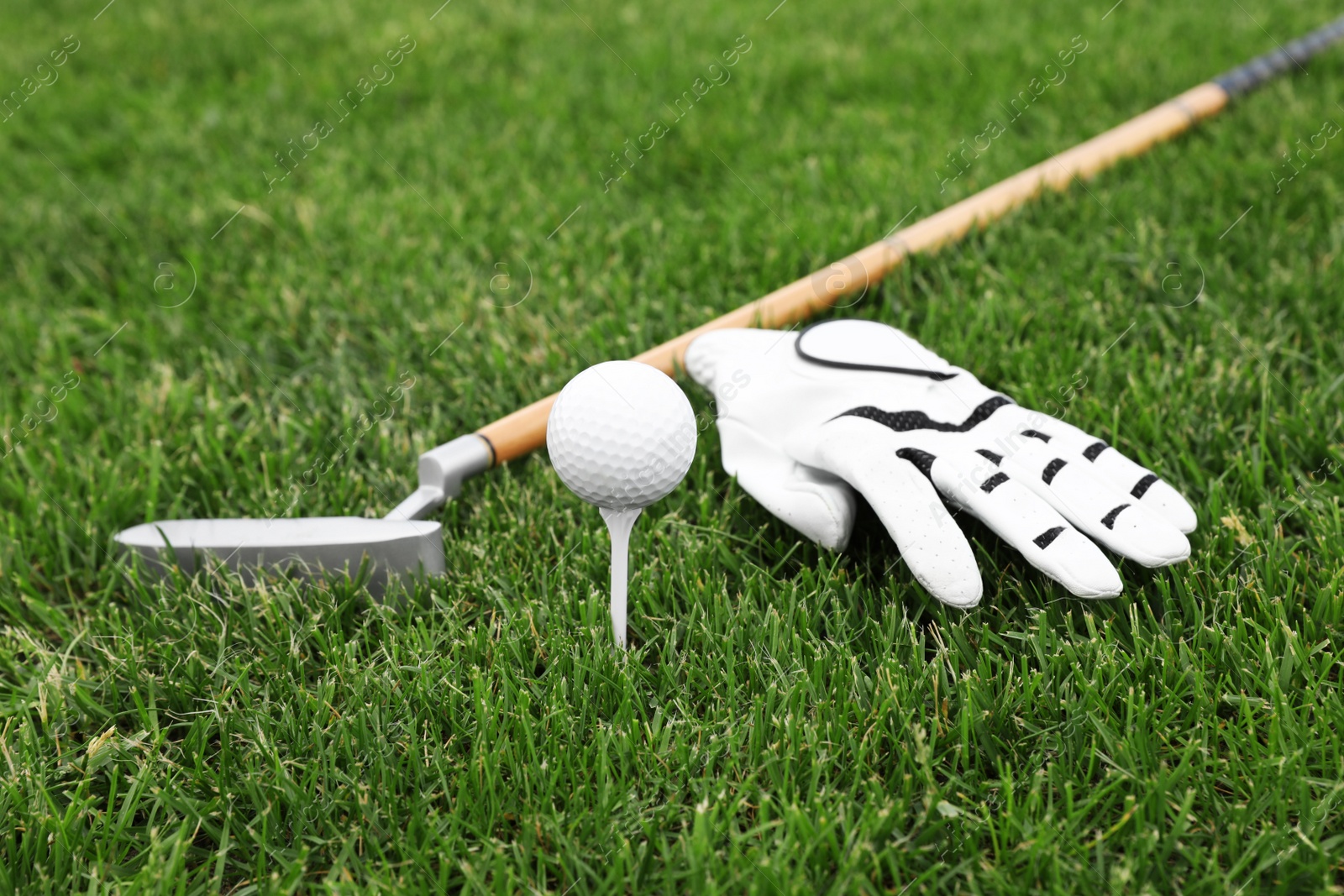 Photo of Golf club with ball, tee and glove on green grass